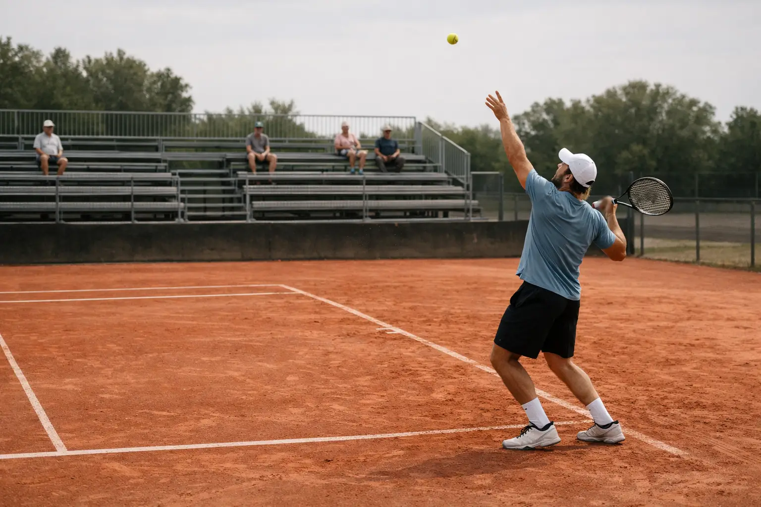 Piccolo campo da tennis di un torneo Challenger con tribune semivuote e giocatore al servizio